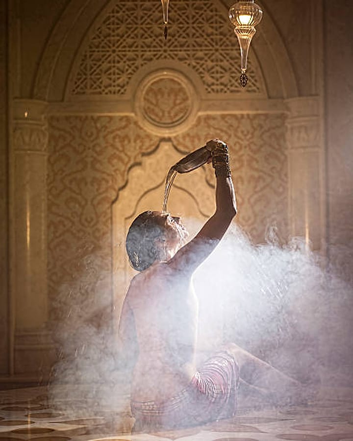 Guest pouring warm water in the steam of a traditional Turkish bath (hamam)